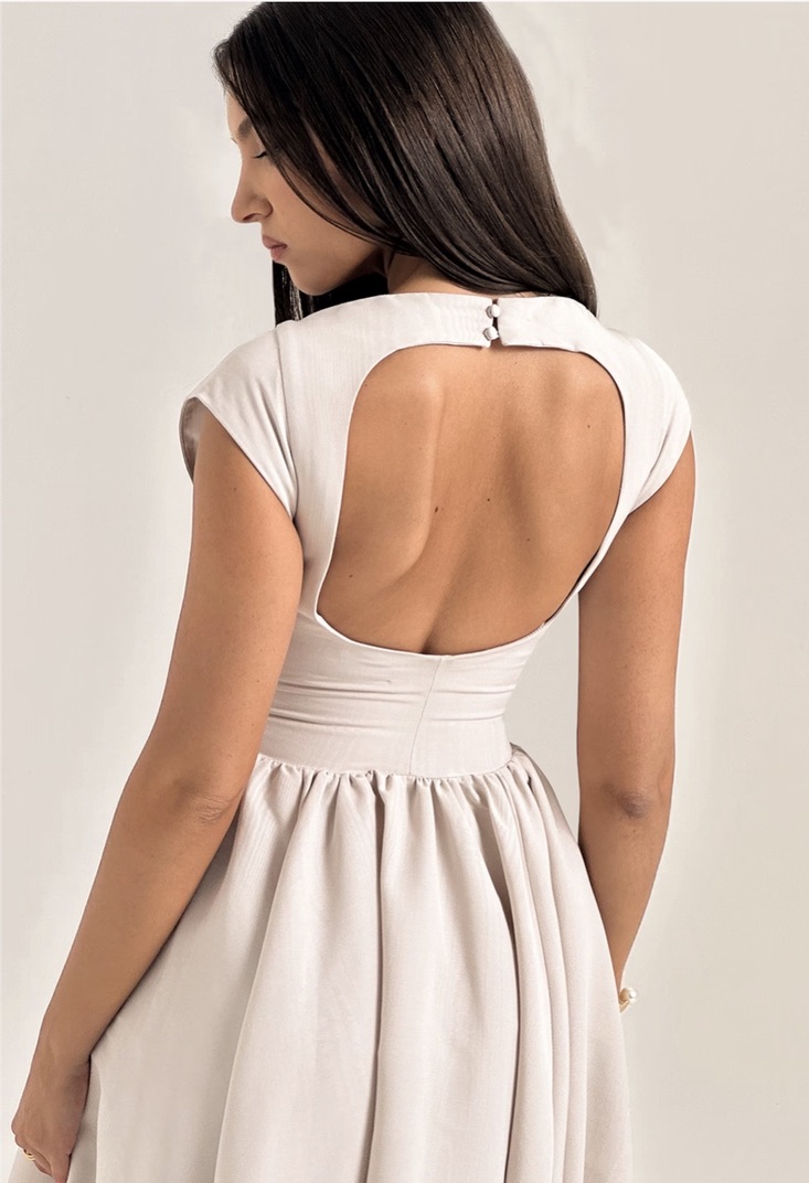 A calf-level dress with flared bottom, a bateau neckline and short cap sleeves. The dress features two side skirt panels inserted at the sides to add volume to the dress. The inserted skirt features a top curve starting 5cm away from the centre front and at the hip level and curving up to meet the side seam at 4cm below the waist level, continuing to the back at the same level to form a back skirt. The curve is delimited by a straight vertical seam at the front running to the dresses' hem. The side skirt upper curve is gathered to provide volume and the entire hem curve is flared. The front features only 3 panels: 1 center front panel, two side skirts. The back features two centre back panels split in the middle by the center back seam for zipper insertion, a full gathered skirt. The side skirts from the front and back are merged together. The front features a curved dart starting at the bust apex, through the underbust, the waist and stopping at the inserted skirt curved hem at 4cm after it starts. Hence the front contains the necklines, the shoulder line, the armhole, the side seams, the portion of the upper side skirt before the dart, the two dart legs, the front side skirt curve, and the side skirt vertical seam, and the part of the front hem corresponding to the center front panels. The center front panel is mirrored across the center front. The dress features a 2cm shoulder line and an open boat neckline. The sleeves are cap sleeves featuring only a sleeve cap and a sleeve hem. The sleeve cap is similar to the armhole shape only starting 4cm to the left and right of the bottom armhole. The back of the dress features an open back, with a circular cutout starting at 3cm below the back neck, going to the mid shoulder level and turning down to the bottom of the shoulder blade to curve back again at the center back.